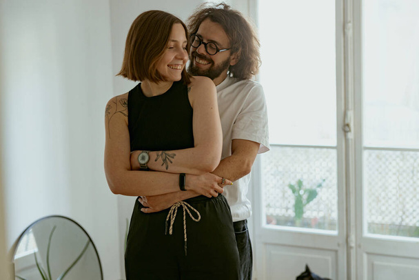 Mann und Frau umarmen sich im Wohnzimmer mit Liebe und Zärtlichkeit. Gute Beziehungszeit - Foto, Bild