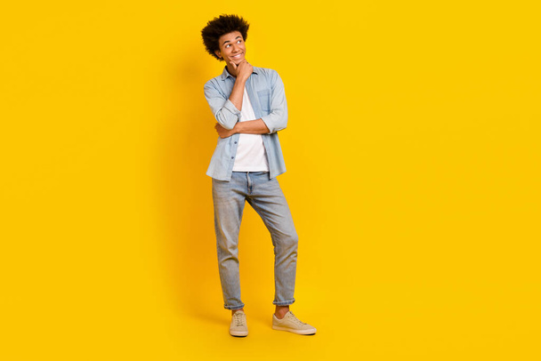 Full length photo of minded positive man arm touch chin look empty space isolated on yellow color background. - Zdjęcie, obraz