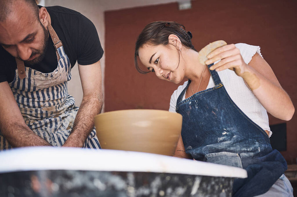 Mieć i kształtować. młody mężczyzna i kobieta pracujący z gliną w pracowni garncarskiej - Zdjęcie, obraz
