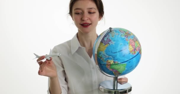 Viajar en avión mundial y vender billetes de avión. Hermosa chica sosteniendo avión y globo con mapa del mundo en las manos - Imágenes, Vídeo