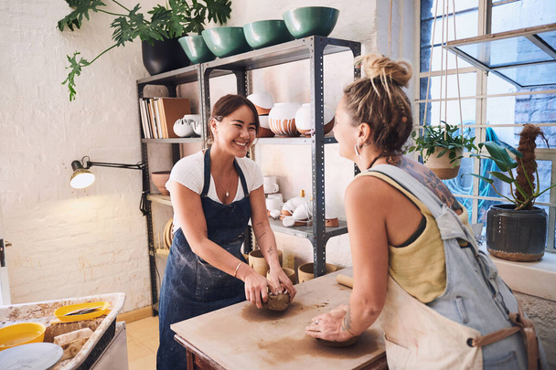 The world is a happier place with art in it. two young women kneading clay in a pottery studio - Фото, изображение