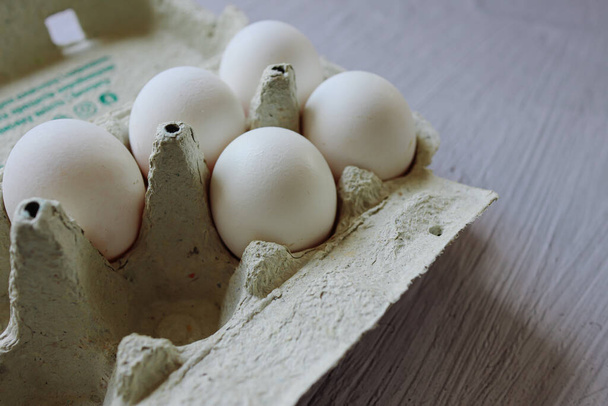 white chicken eggs on a green background.cardboard box with eggs.white chicken egg.home farm.ingredients.cooking in the kitchen.lots of eggs.cooking as a hobby.selling eggs.packaged eggs.shell.organic food.quality product.proper nutrition.  - Zdjęcie, obraz