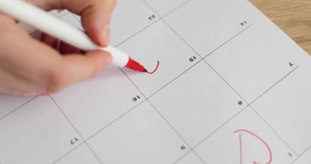 Woman hand draws red heart on calendar on day of date with man. Wedding day - Footage, Video