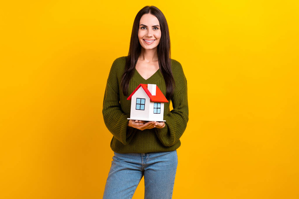 Portrait of cheerful friendly person arms hold little house toothy smile isolated on yellow color background. - Foto, Imagem