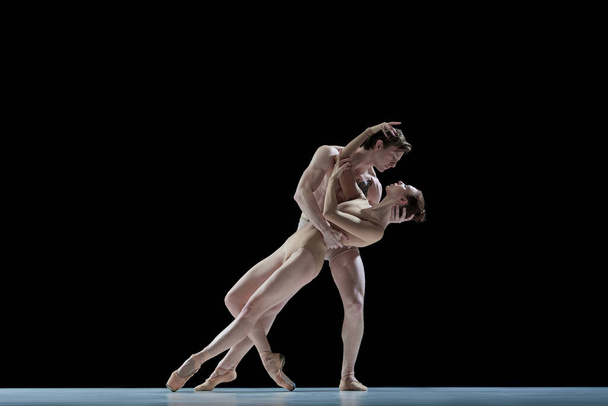 Love and passion. Young people, man and woman, professional ballet dancers making performance against black studio background. Concept of beauty, classical dance style, inspiration, movements. Ad - Foto, Bild