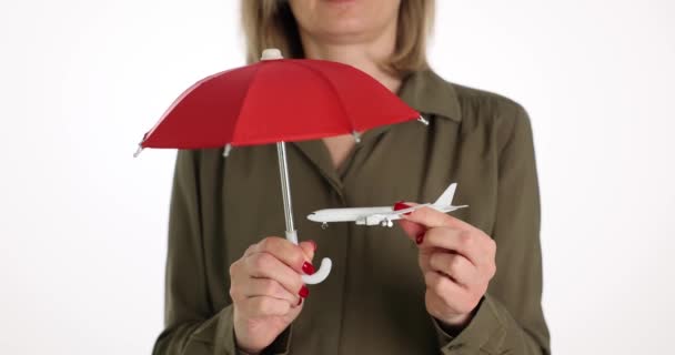 Woman is holding umbrella and toy plane. Air travel safety - Footage, Video