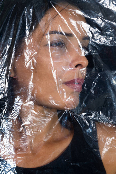 Kobieta z plastikową torbą na głowie. Protest przeciwko stosowaniu tworzyw sztucznych na świecie. Problemy środowiskowe. Izolacja na czarnym tle. - Zdjęcie, obraz