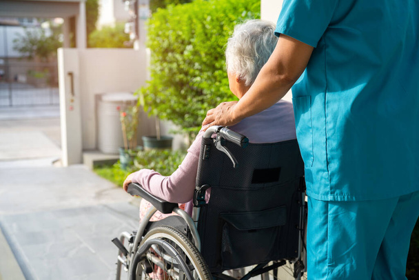 Bakıcı yardım ve bakım Asyalı yaşlı kadın hasta tekerlekli sandalyede hemşire hastanesinde rampaya oturuyor, sağlıklı güçlü tıbbi konsept.. - Fotoğraf, Görsel