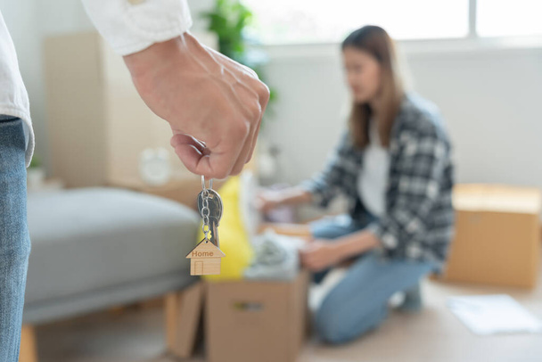Moving house, relocation. Couple hold key house keychain in new apartment, inside the room was a cardboard box containing personal belongings and furniture. move in the new apartment or condominium - Foto, Imagem