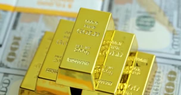 Aranyrudak forgatása dollárbankjegyek hátterében. Aranyrudak az amerikai bankjegyeken közelkép - Felvétel, videó