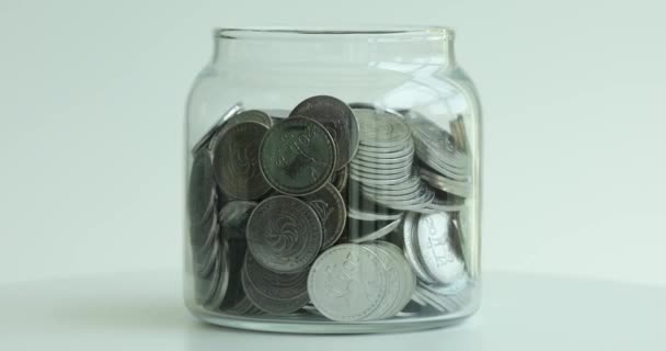 Glass jar piggy bank rotating on white background. Accumulation of cash financial investments - Footage, Video