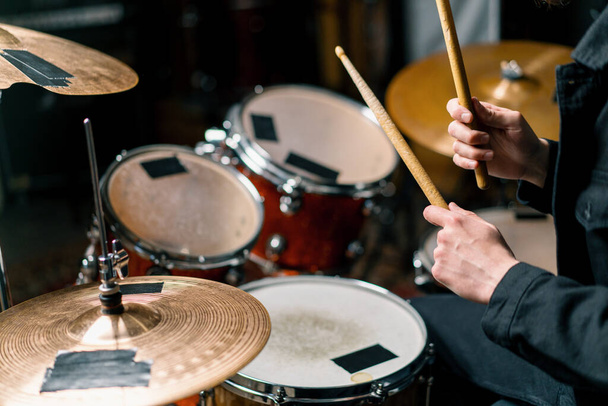 baterista toca un kit de batería en un estudio de grabación en un ensayo de músico profesional grabación de una canción golpea los palos en el primer plano del instrumento - Foto, imagen