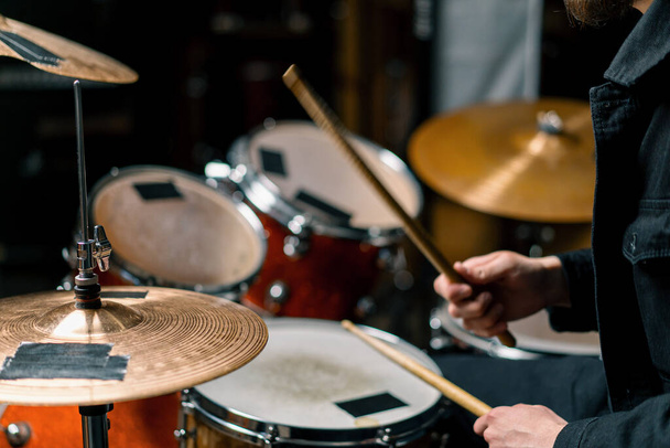 drummer plays a drum kit in a recording studio at a professional musician rehearsal recording a song beats the sticks on the instrument closeup - Zdjęcie, obraz