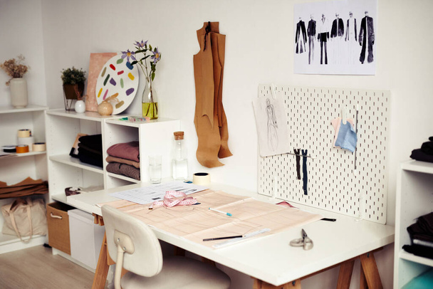 Paper with drawn sewing pattern and sketches on desk in fashion studio of designer - Photo, Image