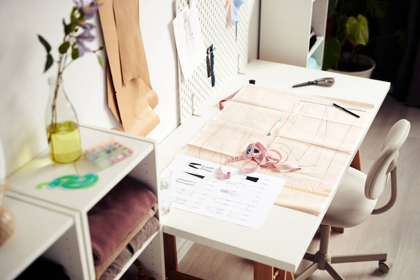 Sheet with fashion sketches, sewing pattern and measuring tape on desk of tailor or designer - 写真・画像