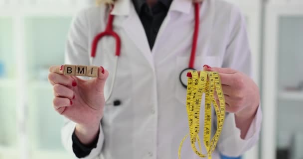 El doctor sostiene la palabra IMC y la cinta métrica. Nutricionista recomienda un estilo de vida saludable - Metraje, vídeo