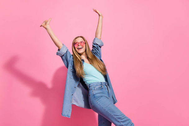 Photo portrait of pretty young teenager girl walk raise hands look empty space wear trendy jeans outfit isolated on pink color background. - Foto, immagini