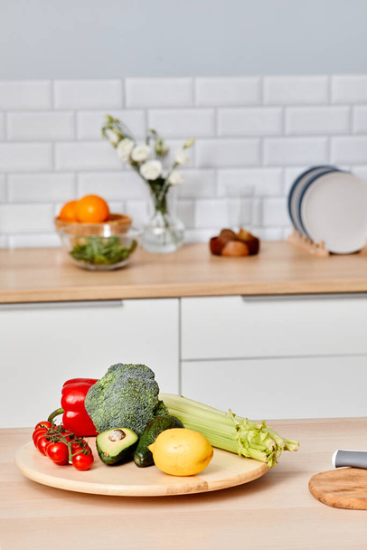 Vertikales Bild von frischem Gemüse auf Holzbrettern auf dem Tisch in der Küche bei der Vorbereitung für vegetarisches Gericht - Foto, Bild