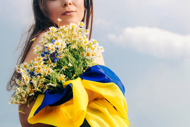 Oekraïense meisje met een blauw-gele vlag in haar handen op de achtergrond van de fiel - Foto, afbeelding