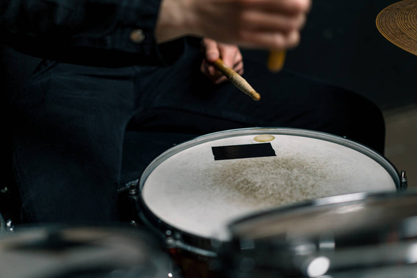 drummer speelt drumstel in een opnamestudio bij een professionele muzikant repetitie opname van een nummer verslaat de stokken op het instrument close-up - Foto, afbeelding