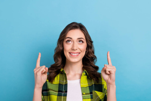 Photo of good mood woman with curly hairdo dressed checkered shirt look directing at sale empty space isolated on blue color background. - Foto, Bild