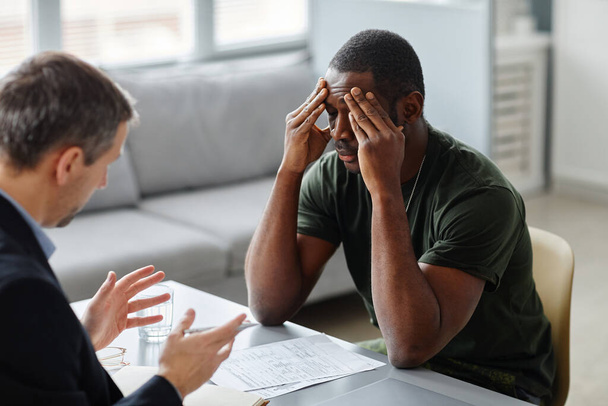 Poszttraumás stresszben szenvedő fiatal afro-amerikai katonával terápiás kezelésben részesülő professzionális pszichiáter - Fotó, kép