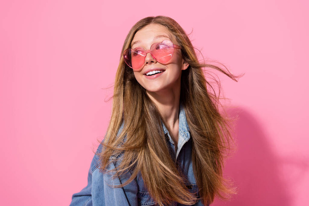 Photo portrait of pretty young teen girl fluttering hair look empty space dressed stylish denim outfit isolated on pink color background. - Fotó, kép