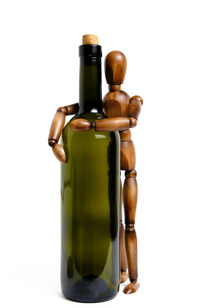 Standing wooden mannequin hugs an empty bottle of wine.Concept of alcohol abuse and dependence - Foto, Imagem