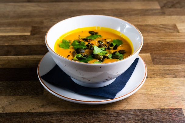 Pumpkin and carrot soup with cream and parsley on a dark wooden background - Φωτογραφία, εικόνα