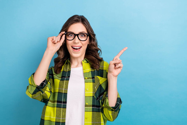 Portrait of astonished positive lady touch eyewear direct finger empty space offer isolated on blue color background. - Photo, Image