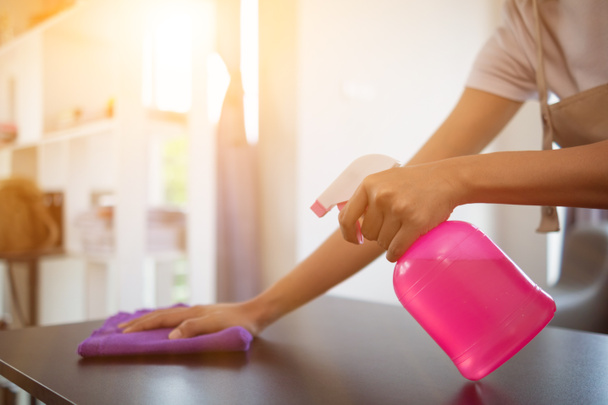 Cleaning staff is wiping cloth with cleaner and disinfectant on the surface of table to make the table clean with cleaning products and free from germs clinging to surface of the table in living room. - Photo, Image