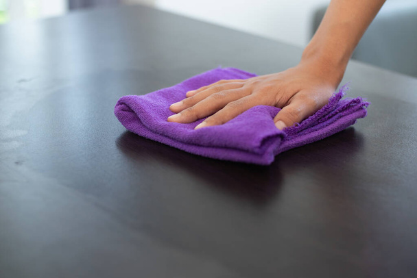 Il personale di pulizia pulisce il panno con detergente e disinfettante sulla superficie del tavolo per rendere il tavolo pulito con prodotti per la pulizia e privo di germi aggrappati alla superficie del tavolo in soggiorno.. - Foto, immagini