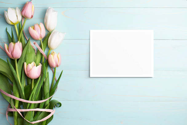 Composition of pink and white tulips, ribbons, blank card on blue wooden background. Tulips spring bouquet. Content for Birthday, Valentines Day, Womens day. Flat lay, top view, close up, copy space. - Fotó, kép