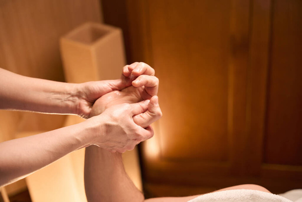 Cropped photo of qualified masseuse massaging palms of adult male client using thumbs - Photo, Image