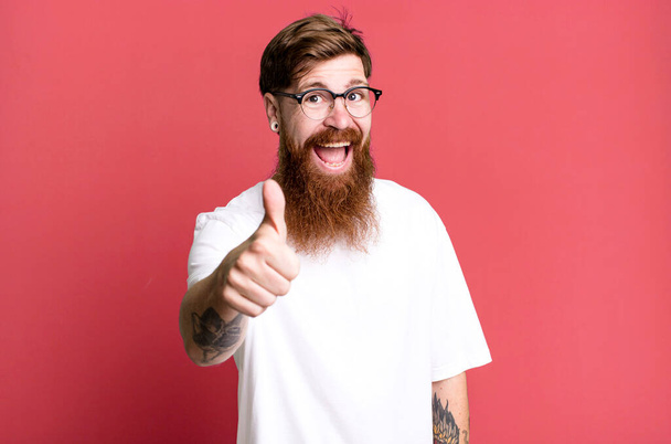 long beard and red hair man feeling proud,smiling positively with thumbs up - 写真・画像