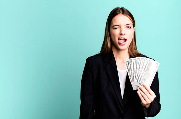 young pretty woman with cheerful and rebellious attitude, joking and sticking tongue out. business and dolla banknotes concept - Foto, Imagem