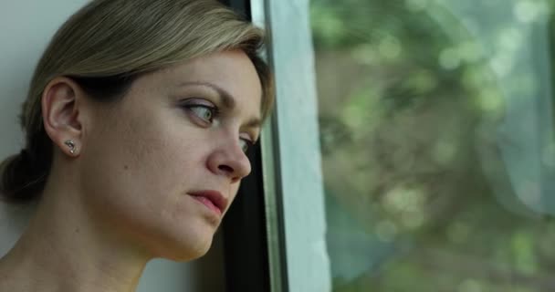Грустная одинокая женщина скучает и смотрит в окно. Депрессия эмоционального стресса и одиночество - Кадры, видео