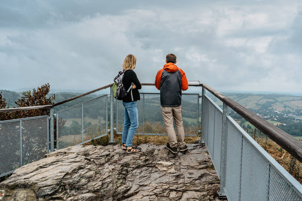 Couple of hikers together enjoying view of nature.Autumn fall outdoor cold season.Man and woman backpackers on viewing platform.Leisure activity concept.Sporty caucasian adults in mountains. - Photo, image
