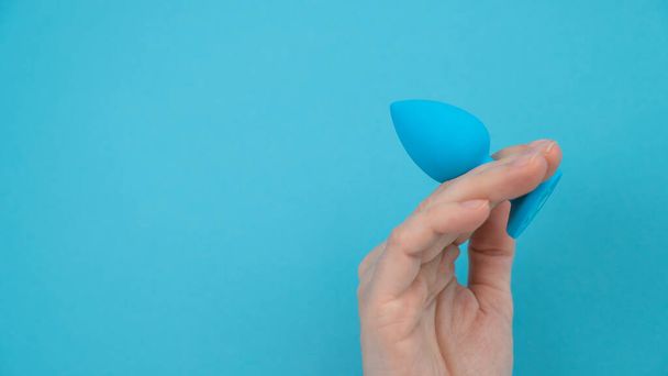 Woman holding a blue anal plug on a blue background - Foto, Imagen