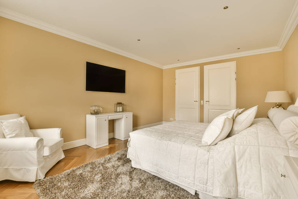 um quarto com uma cama, cadeira e tv tela plana na parede na sala é muito amarelo claro - Foto, Imagem