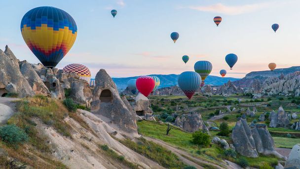 Cappadocia Turkey. Hot air balloons flying over fairy chimneys at sunrise in Cappadocia. Travel to Turkey. Touristic landmarks of Turkiye. Selective focus included - Фото, зображення