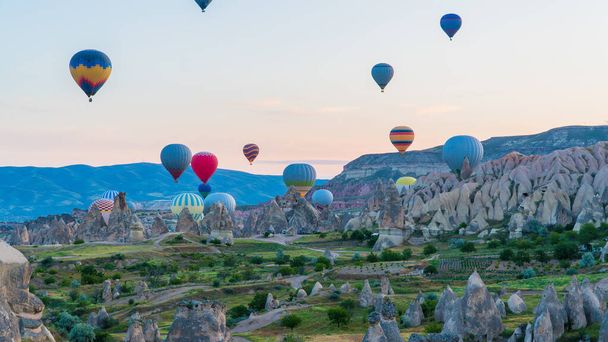 Cappadocia Turkey. Hot air balloons flying over fairy chimneys at sunrise in Cappadocia. Travel to Turkey. Touristic landmarks of Turkiye. Selective focus included - Zdjęcie, obraz