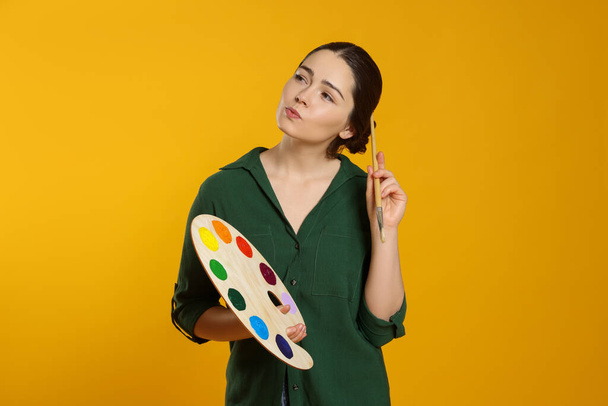 Woman with painting tools on yellow background. Young artist - Foto, Bild