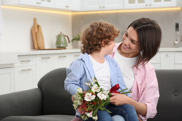 Happy woman with her cute son and bouquet of beautiful flowers at home. Mother's day celebration - Foto, imagen