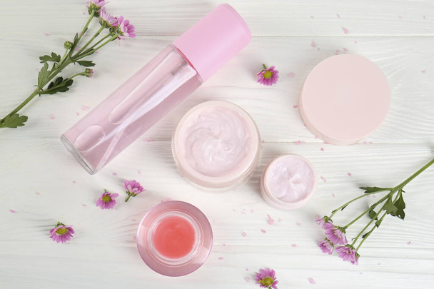 Homemade cosmetic products and beautiful flowers on white wooden table, flat lay - Fotoğraf, Görsel