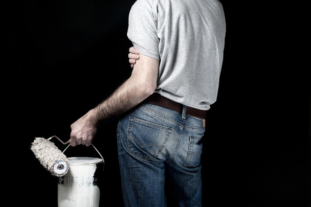 Man holding paint roller and a bucket of paint - Фото, зображення