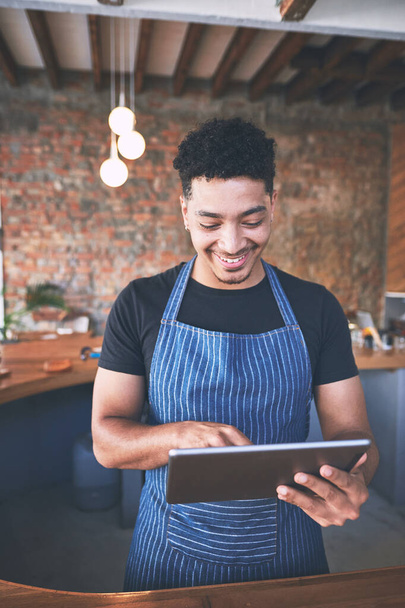 Das intelligenteste Task-Management-Tool. ein selbstbewusster junger Mann, der während seiner Arbeit in einem Café ein digitales Tablet benutzt - Foto, Bild