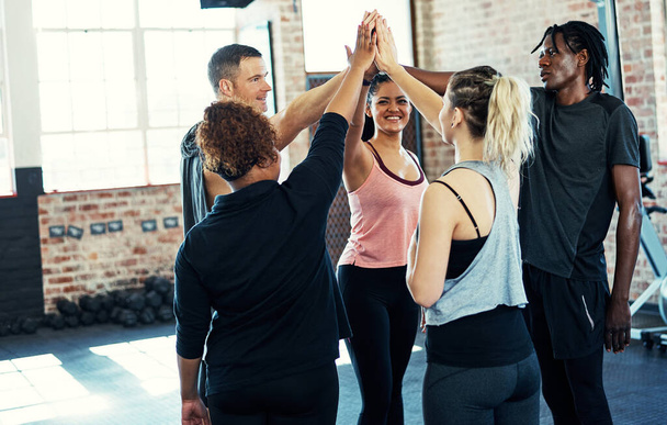 We got this guys. a cheerful young group of people forming a huddle together before a workout session in a gym - Foto, imagen
