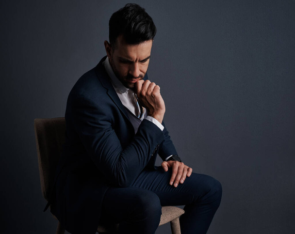 Facing a difficult business decision. Studio shot of a stylish young businessman looking thoughtful against a gray background - Foto, Imagen
