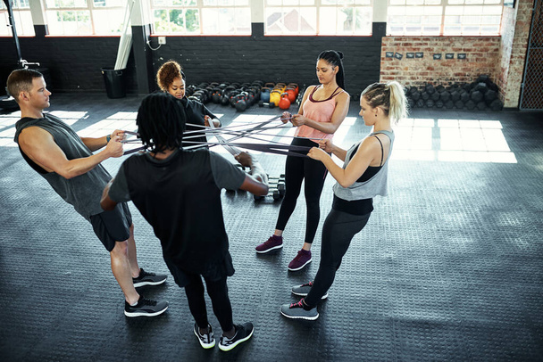 Pomagając sobie nawzajem w osiąganiu celów sprawności. grupa fitness ćwicząca z opaskami oporowymi podczas sesji na siłowni - Zdjęcie, obraz